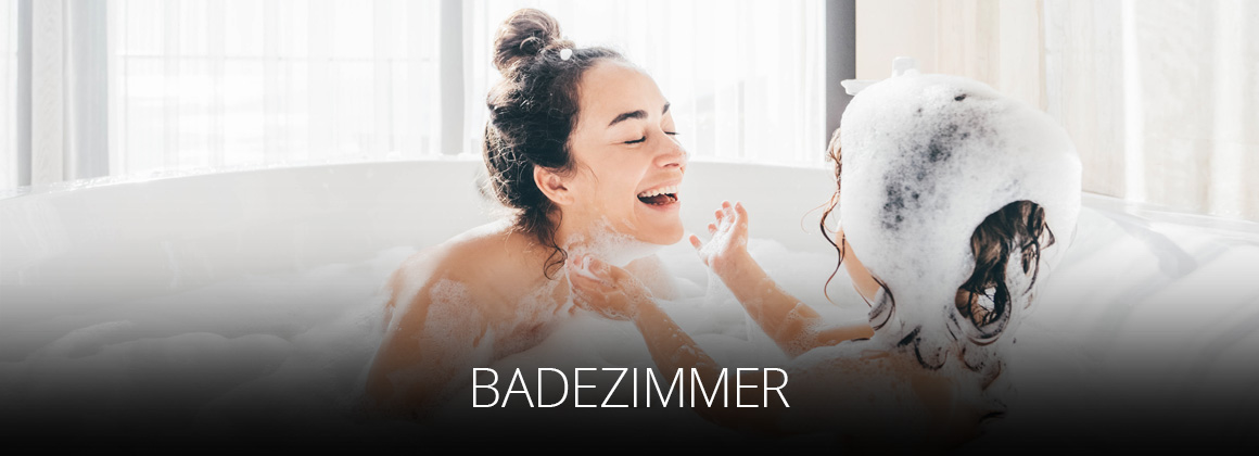 Badezimmer einrichten mit OSTERMANN - Mutter und Tochter haben Freude am Badeschaum in großer Badewanne in hellem, lichtdurchfluteten Badezimmer